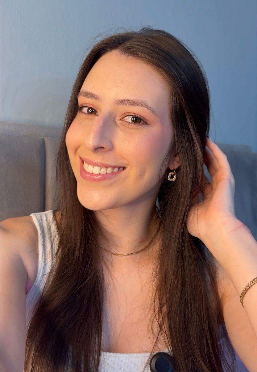 Kassia Vargas sorrindo para a câmera, usando uma blusa clara